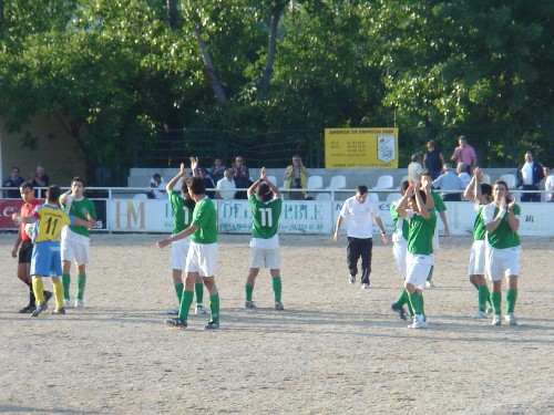Los dos equipos dandose la mano deportivamente en el centro del campo